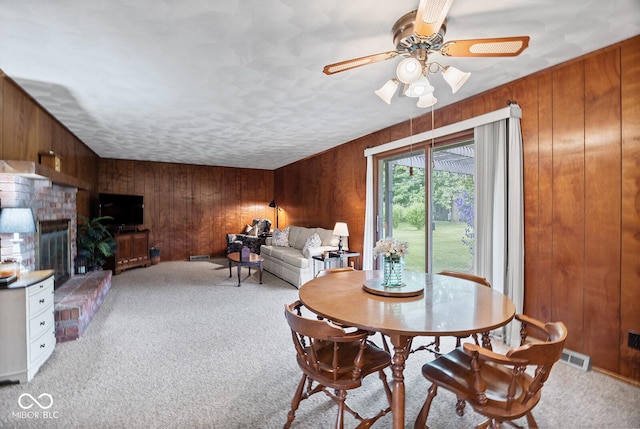 3620 Winter St, Lafayette, IN 47909 - dining area featuring wooden walls, light carpet, a ceiling fan, and a brick fireplace