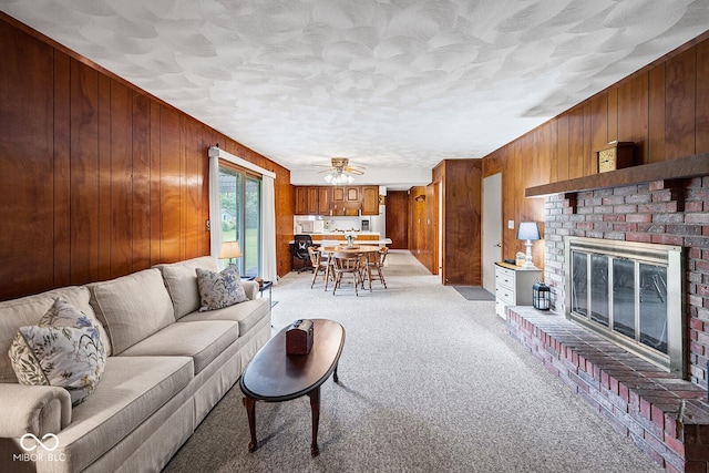 3620 Winter St, Lafayette, IN 47909 - living area featuring wooden walls, light colored carpet, a brick fireplace, ceiling fan, and a textured ceiling