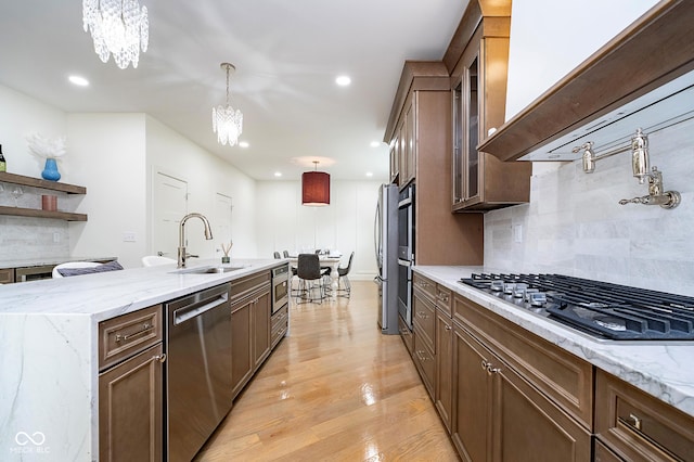 2130 Brookside Pkwy N Drive, Indianapolis, IN 46201 - kitchen featuring appliances with stainless steel finishes, a chandelier, decorative backsplash, light wood-type flooring, and decorative light fixtures