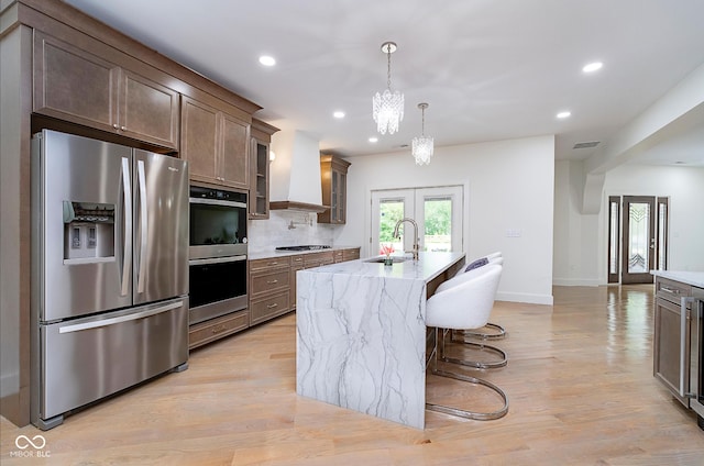 2130 Brookside Pkwy N Drive, Indianapolis, IN 46201 - kitchen featuring stainless steel appliances, a kitchen island with sink, recessed lighting, french doors, and light stone countertops