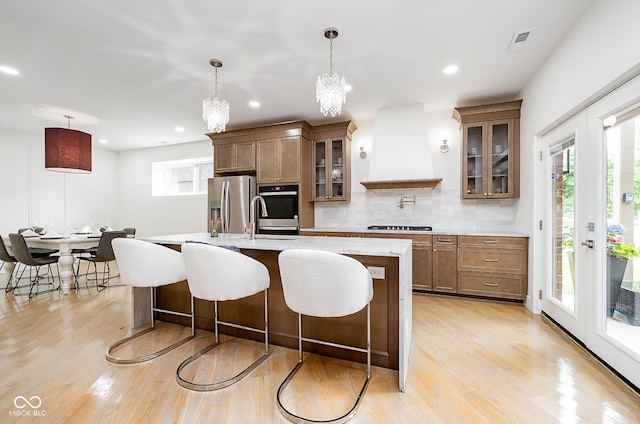 2130 Brookside Pkwy N Drive, Indianapolis, IN 46201 - kitchen featuring stainless steel appliances, custom range hood, light countertops, light wood finished floors, and a kitchen bar