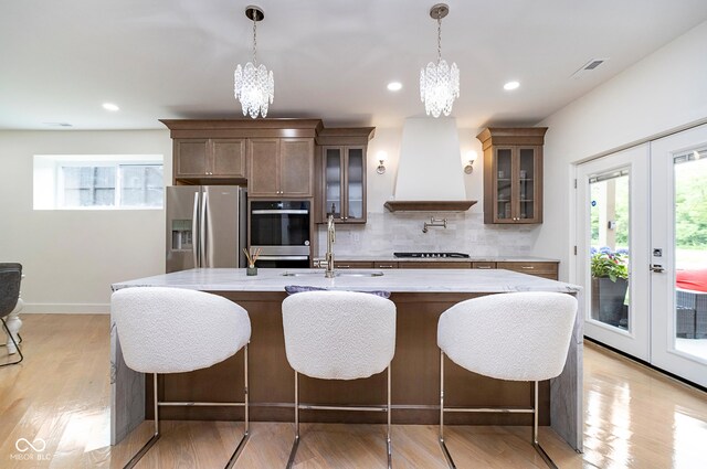2130 Brookside Pkwy N Drive, Indianapolis, IN 46201 - kitchen featuring stainless steel appliances, custom range hood, a chandelier, decorative backsplash, and glass insert cabinets