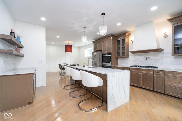 2130 Brookside Pkwy N Drive, Indianapolis, IN 46201 - kitchen with backsplash, gas stovetop, a breakfast bar, a kitchen island with sink, and stainless steel fridge