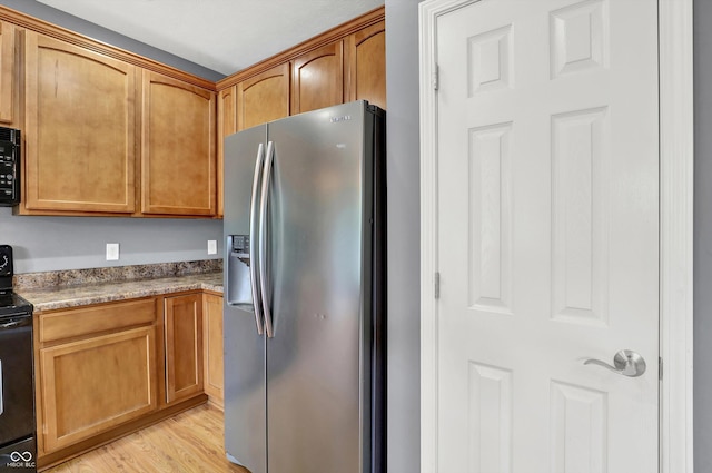 5674 Brownstone Dr, Indianapolis, IN 46220 - kitchen featuring stainless steel fridge with ice dispenser, range with electric stovetop, light wood-style floors, black microwave, and brown cabinetry