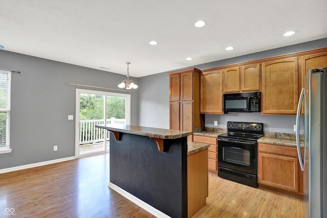 5674 Brownstone Dr, Indianapolis, IN 46220 - kitchen with black appliances, light wood-style flooring, a chandelier, a breakfast bar area, and a center island