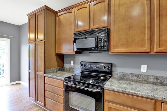 5674 Brownstone Dr, Indianapolis, IN 46220 - kitchen featuring black appliances, light wood finished floors, brown cabinetry, and light stone counters