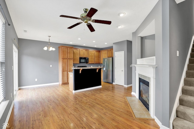 5674 Brownstone Dr, Indianapolis, IN 46220 - kitchen featuring stainless steel refrigerator with ice dispenser, black microwave, light wood-type flooring, a kitchen island, and a ceiling fan