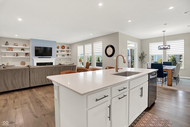 1319 Petit Verdot Dr, Westfield, IN 46074 - kitchen with dishwasher, light wood-style floors, a kitchen island with sink, light countertops, and a fireplace