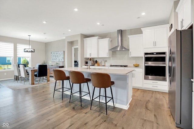 1319 Petit Verdot Dr, Westfield, IN 46074 - kitchen with appliances with stainless steel finishes, wall chimney range hood, an island with sink, white cabinets, and recessed lighting