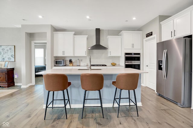 1319 Petit Verdot Dr, Westfield, IN 46074 - kitchen featuring stainless steel appliances, wall chimney range hood, backsplash, white cabinets, and light wood-style flooring