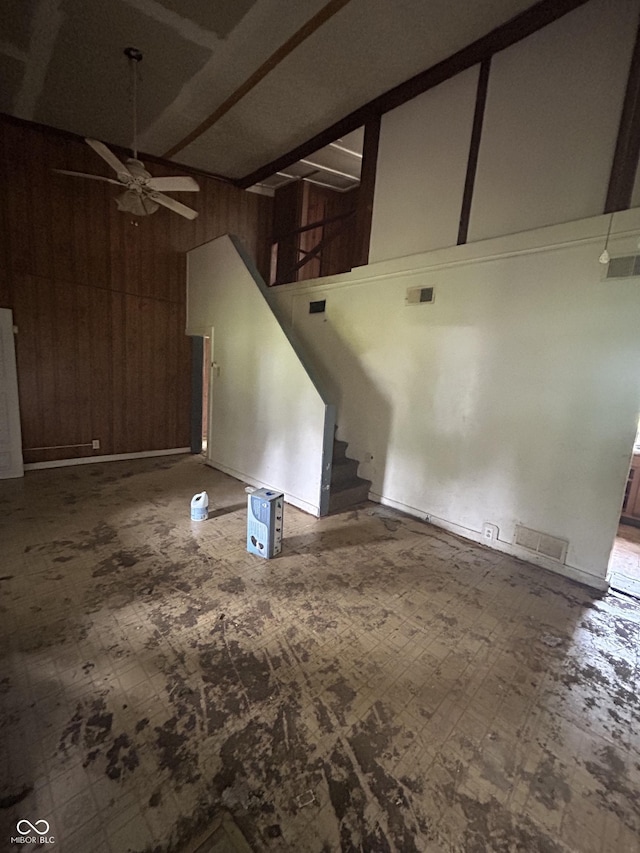 1330 Schleicher Ave, Indianapolis, IN 46229 - unfurnished living room featuring ceiling fan, wood walls, high vaulted ceiling, stairway, and beamed ceiling