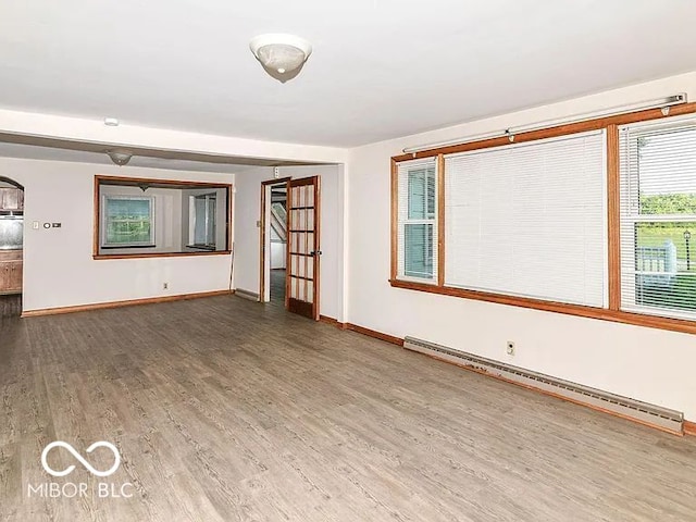 18378 Southeastern Pkwy, Fortville, IN 46040 - unfurnished living room featuring baseboard heating, wood finished floors, and arched walkways
