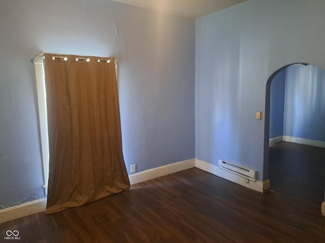 103 N Chester Ave, Indianapolis, IN 46201 - empty room featuring a baseboard heating unit, arched walkways, and wood finished floors