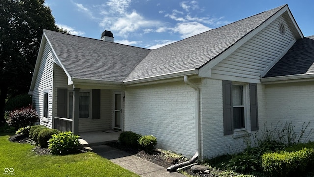 2083 Kerns Ct, Carmel, IN 46280 - view of side of home with brick siding, a chimney, a shingled roof, and a porch