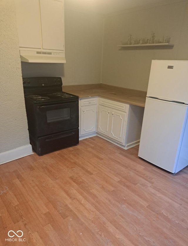 2249 E Brookside Ave, Indianapolis, IN 46218 - kitchen with black range with electric cooktop, freestanding refrigerator, under cabinet range hood, white cabinets, and light wood-style floors