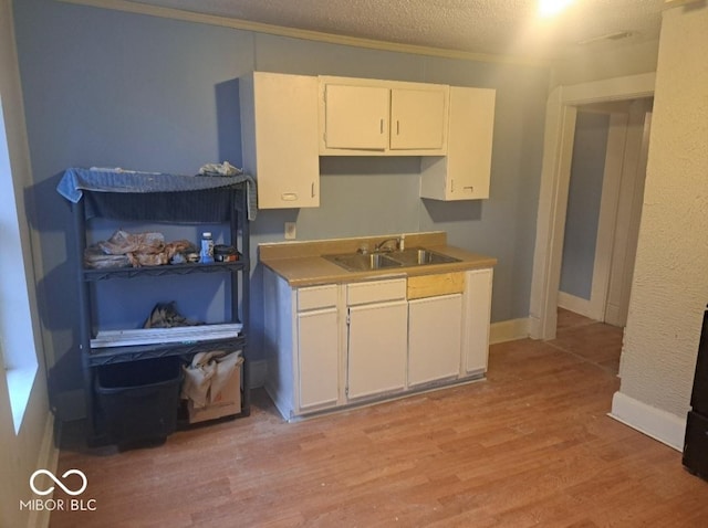 2249 E Brookside Ave, Indianapolis, IN 46218 - kitchen featuring white cabinetry, light wood-style floors, a textured ceiling, and crown molding