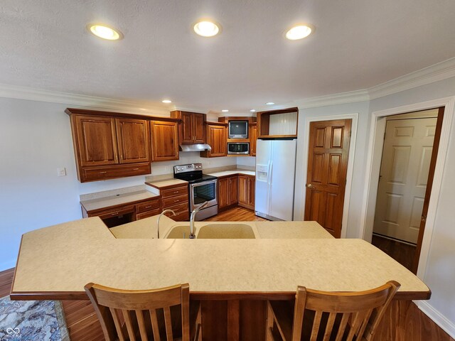 1633 Belfield St, Indianapolis, IN 46217 - kitchen with appliances with stainless steel finishes, under cabinet range hood, a breakfast bar, crown molding, and light countertops