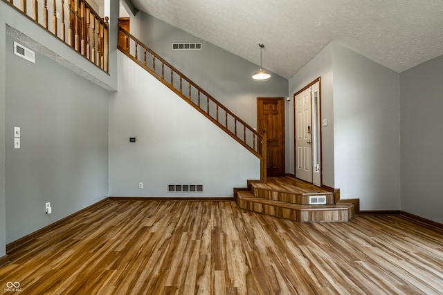 2411 N Willow Way, Indianapolis, IN 46268 - foyer featuring wood finished floors, stairs, a textured ceiling, and high vaulted ceiling