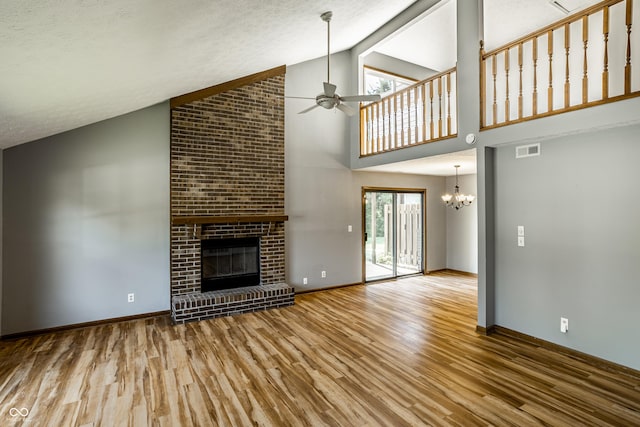 2411 N Willow Way, Indianapolis, IN 46268 - unfurnished living room featuring wood finished floors, a ceiling fan, a fireplace, high vaulted ceiling, and a chandelier