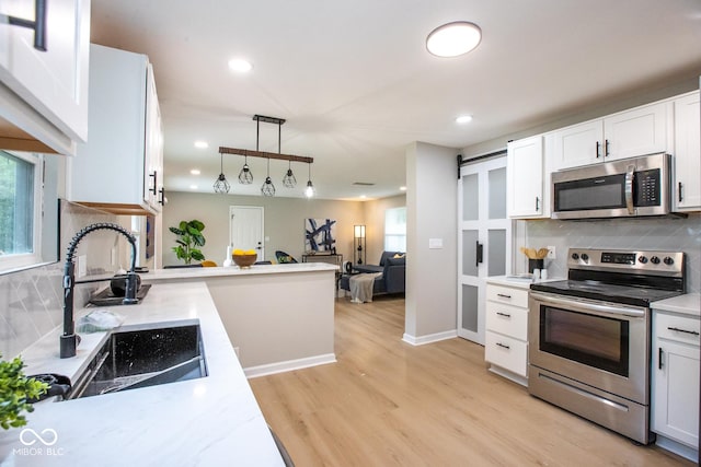 8650 Holliday Dr, Indianapolis, IN 46260 - kitchen featuring stainless steel appliances, decorative backsplash, light wood-style flooring, pendant lighting, and white cabinets