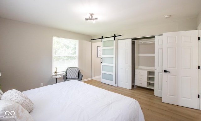 8650 Holliday Dr, Indianapolis, IN 46260 - bedroom featuring light wood finished floors, a barn door, and a closet