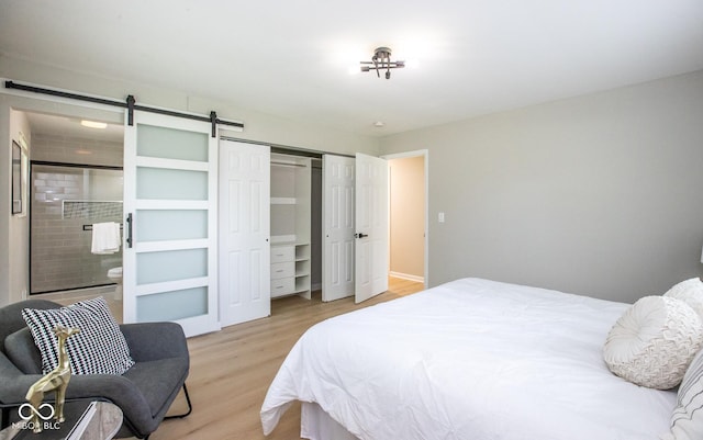 8650 Holliday Dr, Indianapolis, IN 46260 - bedroom featuring light wood-style floors, a closet, ensuite bathroom, and a barn door