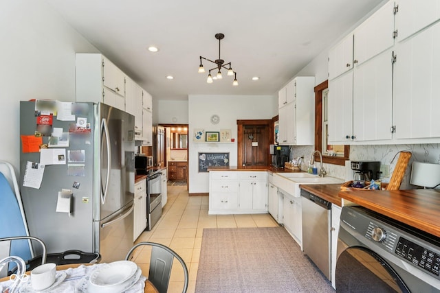 26735 Six Points Rd, Sheridan, IN 46069 - kitchen with stainless steel appliances, washer / dryer, decorative backsplash, light tile patterned floors, and a chandelier