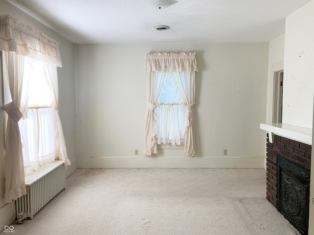 236 N Maple St, Dana, IN 47847 - unfurnished living room with radiator heating unit, light carpet, and a brick fireplace