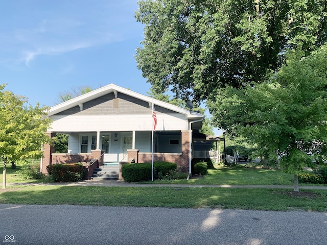 236 N Maple St, Dana, IN 47847 - view of front of house with a porch, brick siding, and a front lawn