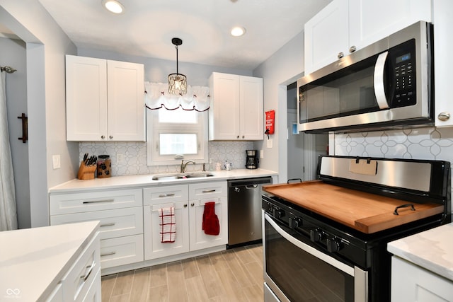 1336 N Butler Ave, Indianapolis, IN 46219 - kitchen with stainless steel appliances, a chandelier, light countertops, white cabinetry, and decorative backsplash