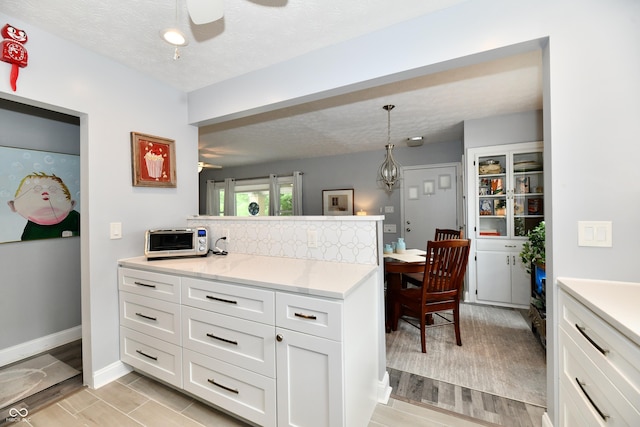 1336 N Butler Ave, Indianapolis, IN 46219 - kitchen featuring ceiling fan, light countertops, white cabinetry, hanging light fixtures, and a peninsula