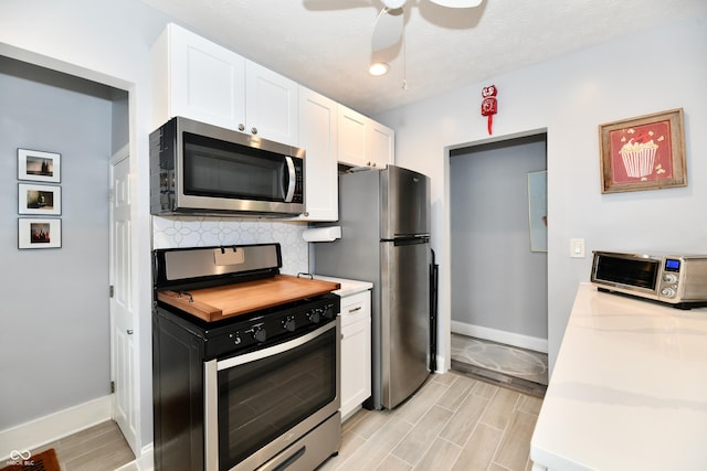 1336 N Butler Ave, Indianapolis, IN 46219 - kitchen with appliances with stainless steel finishes, light countertops, white cabinetry, tasteful backsplash, and wood tiled floors