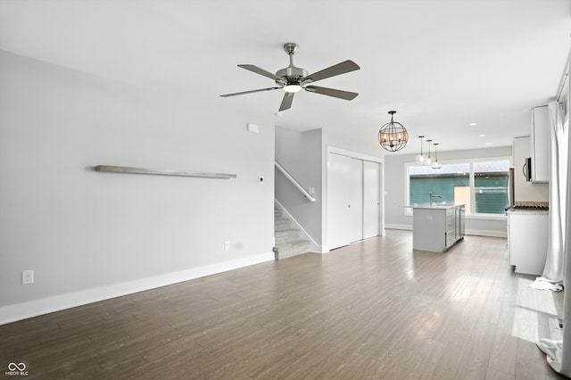 1905 Cornell Ave, Indianapolis, IN 46202 - unfurnished living room with stairs, a ceiling fan, wood finished floors, and a chandelier