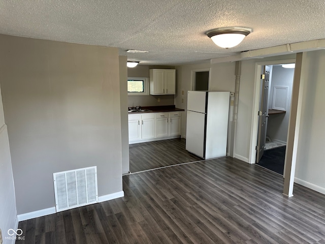 707 S Luick Ave, Muncie, IN 47302 - kitchen featuring freestanding refrigerator, dark wood-style floors, dark countertops, a textured ceiling, and white cabinetry