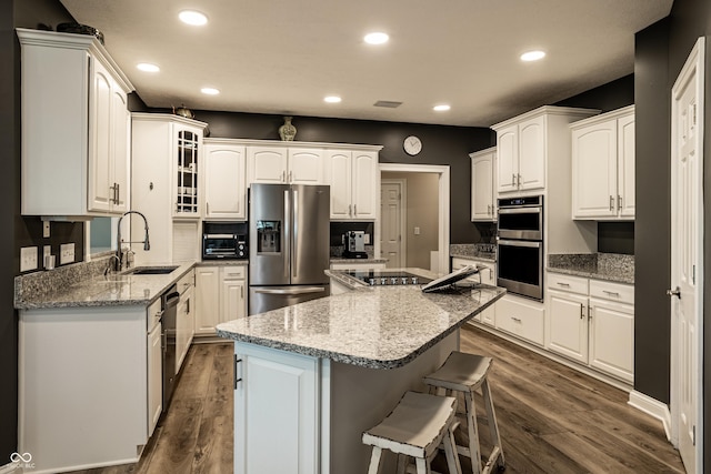 295 Watershed Ct, Noblesville, IN 46062 - kitchen with stainless steel appliances, a breakfast bar area, a kitchen island, dark wood-type flooring, and recessed lighting