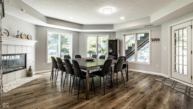 295 Watershed Ct, Noblesville, IN 46062 - dining space with a tray ceiling, a textured ceiling, dark wood-style flooring, and a tile fireplace