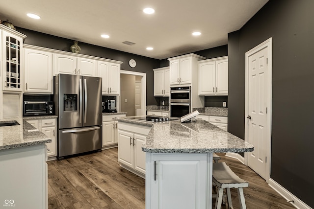 295 Watershed Ct, Noblesville, IN 46062 - kitchen with stainless steel appliances, a center island, a breakfast bar area, dark wood-style flooring, and white cabinetry