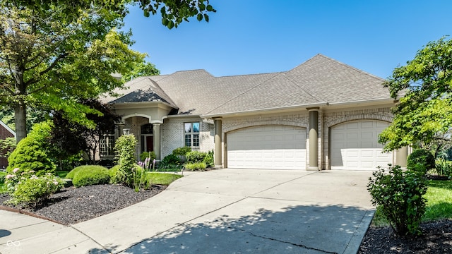 295 Watershed Ct, Noblesville, IN 46062 - french country style house featuring a garage, concrete driveway, a shingled roof, and brick siding