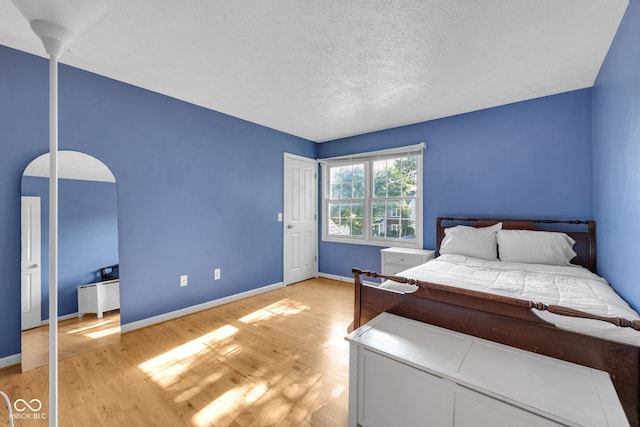 8642 Ray Cir, Indianapolis, IN 46256 - bedroom featuring light wood finished floors, a textured ceiling, and arched walkways