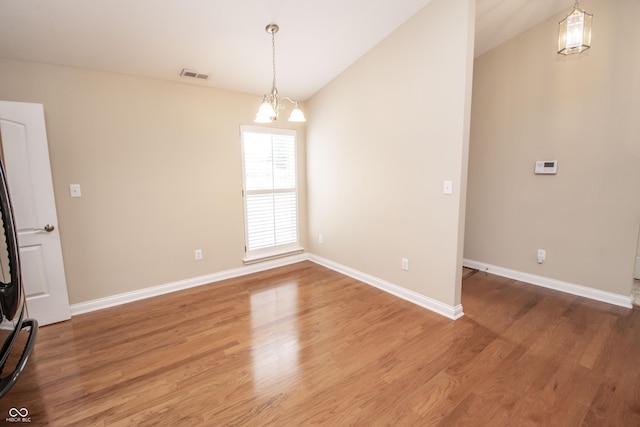 6448 W Whiteside Ct, Greenfield, IN 46140 - unfurnished room with vaulted ceiling, light wood-style floors, and a chandelier