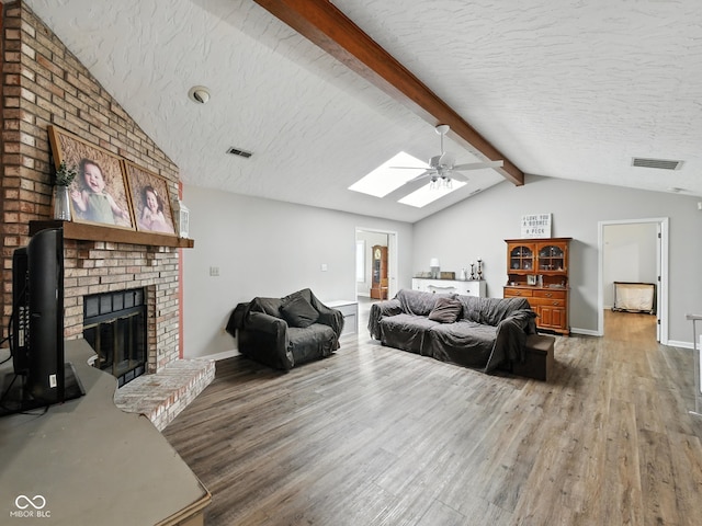 856 Cypress N, Greenwood, IN 46143 - living room featuring wood finished floors, a ceiling fan, a skylight, a fireplace, and a textured ceiling