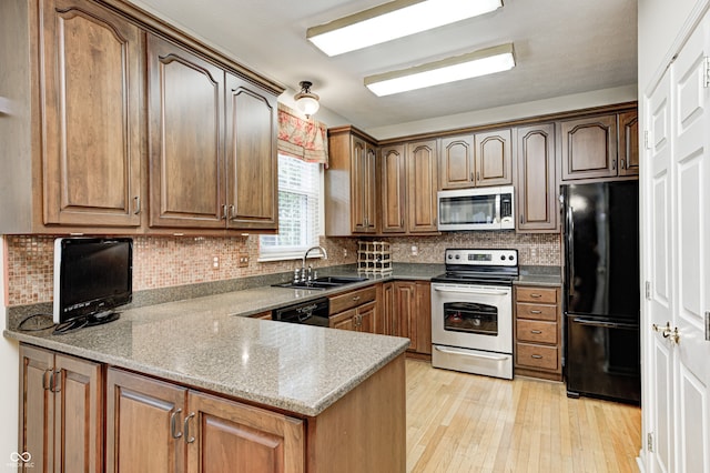 6813 Bluffgrove Dr, Indianapolis, IN 46278 - kitchen featuring black appliances, light wood-style flooring, a peninsula, tasteful backsplash, and brown cabinets