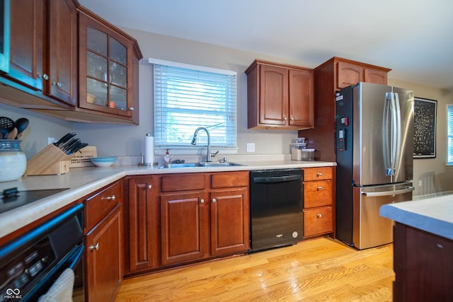 7224 N Tuxedo St, Indianapolis, IN 46240 - kitchen with black appliances, light countertops, glass insert cabinets, and light wood-style floors