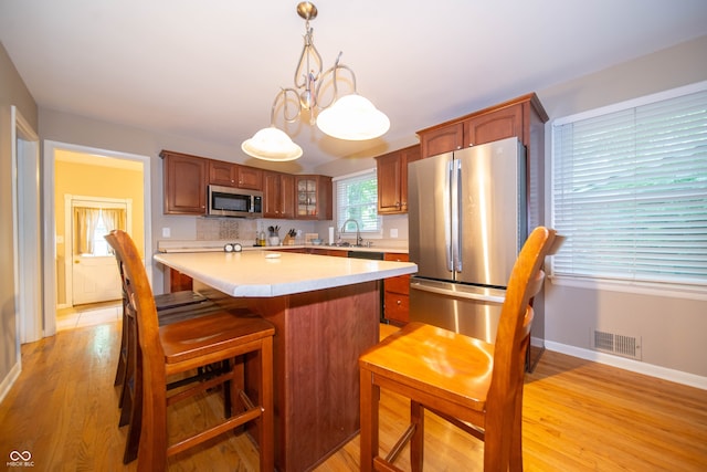 7224 N Tuxedo St, Indianapolis, IN 46240 - kitchen with stainless steel appliances, light countertops, a kitchen island, light wood-style flooring, and glass insert cabinets