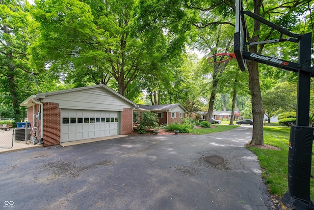 7224 N Tuxedo St, Indianapolis, IN 46240 - view of side of home with asphalt driveway, brick siding, an attached garage, and view of wooded area