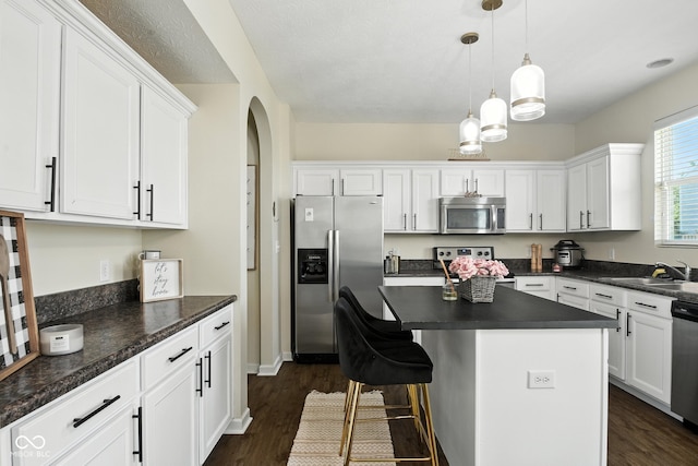 5664 Crump Ln, Indianapolis, IN 46234 - kitchen featuring stainless steel appliances, dark countertops, arched walkways, white cabinetry, and dark wood finished floors