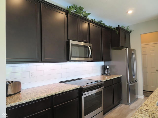 2272 Trefoil Dr, Plainfield, IN 46168 - kitchen featuring stainless steel appliances, light stone counters, light wood-type flooring, tasteful backsplash, and recessed lighting