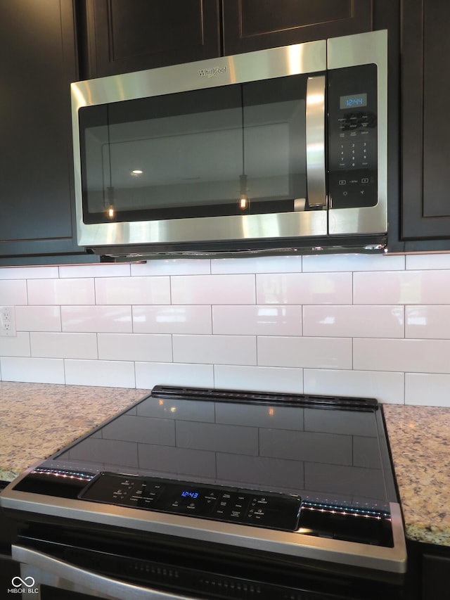 2272 Trefoil Dr, Plainfield, IN 46168 - kitchen view of stainless steel microwave, black electric range, tasteful backsplash, and light stone countertops