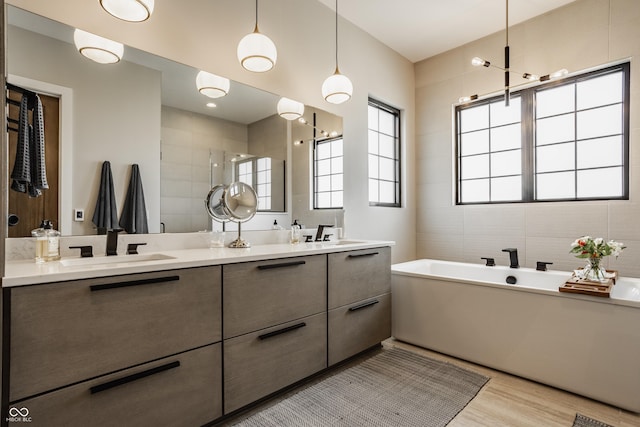 12022 Otto Ln, Carmel, IN 46032 - full bath featuring double vanity, a soaking tub, wood finished floors, tile walls, and a tile shower
