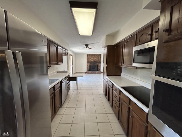 4675 N Riverside Dr, Columbus, IN 47203 - kitchen featuring appliances with stainless steel finishes, ceiling fan, light tile patterned flooring, light countertops, and a brick fireplace
